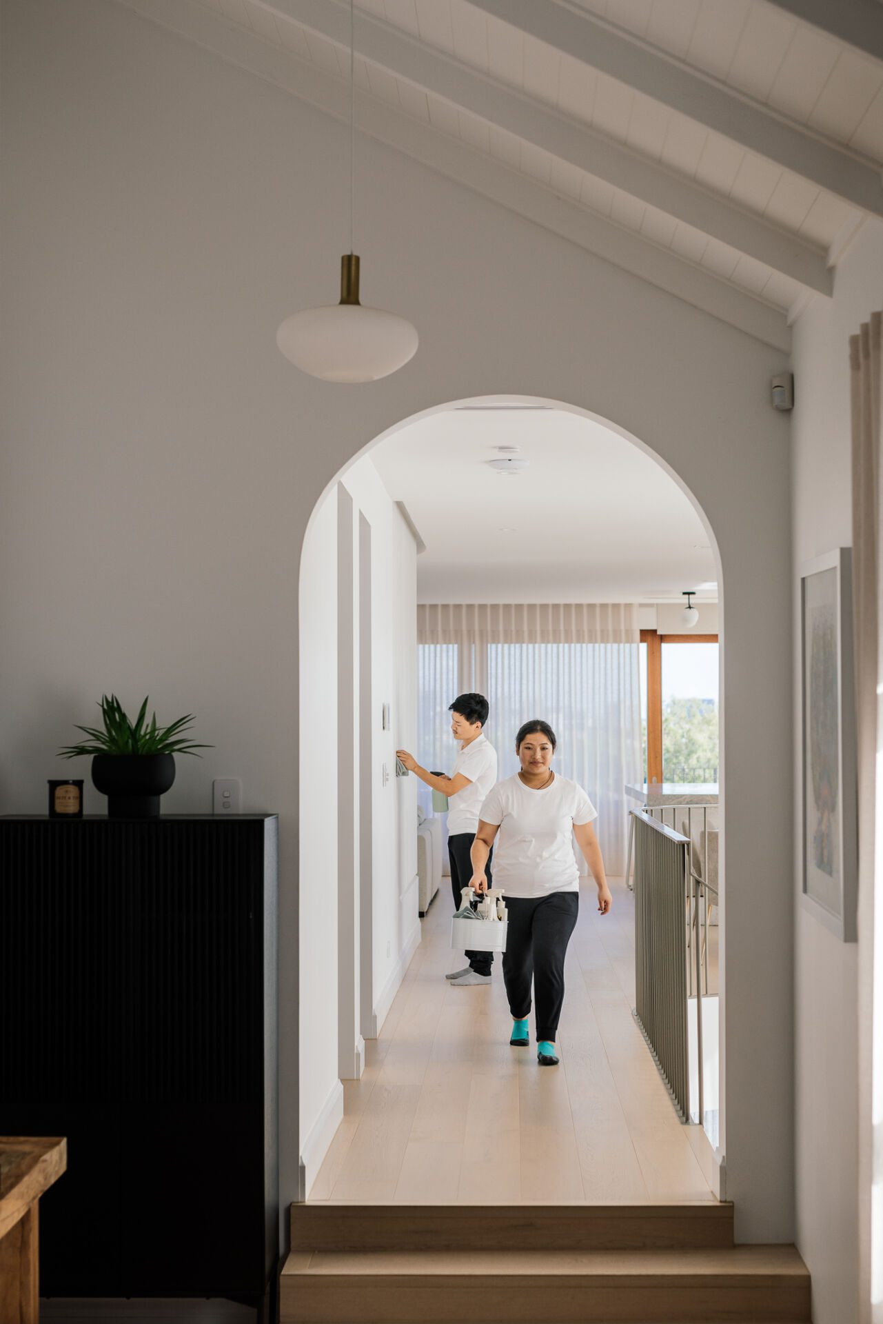 Two Family Clean crew members walking through a Sydney home with a cleaning caddy